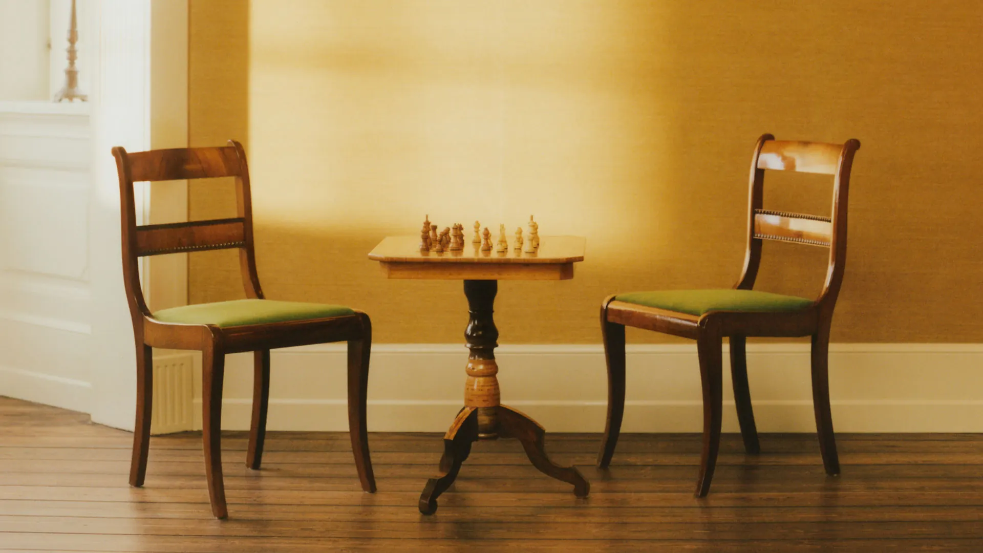 Two chairs and a chess table in a warm Villa Hesnæs room.