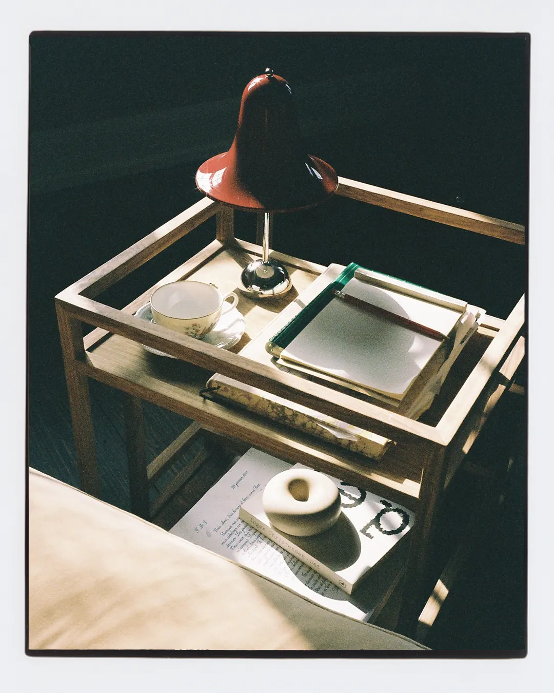 A bedside tray with a lamp, cup, candle, and papers at Villa Hesnæs.