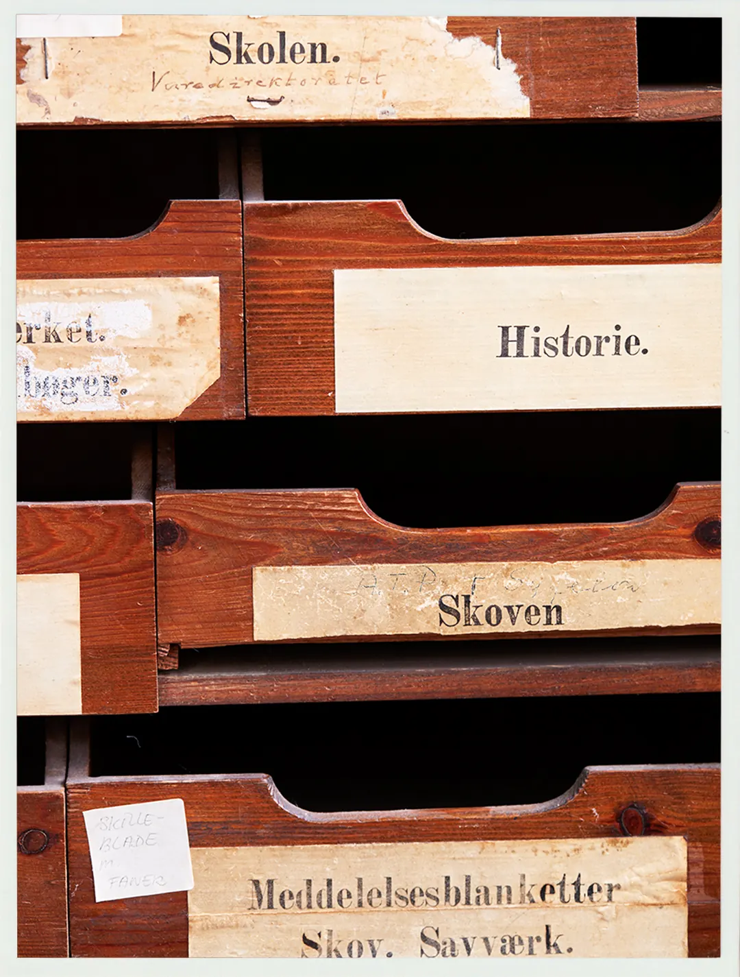 Wooden archive drawers labelled with school, history, forest, and crafts.