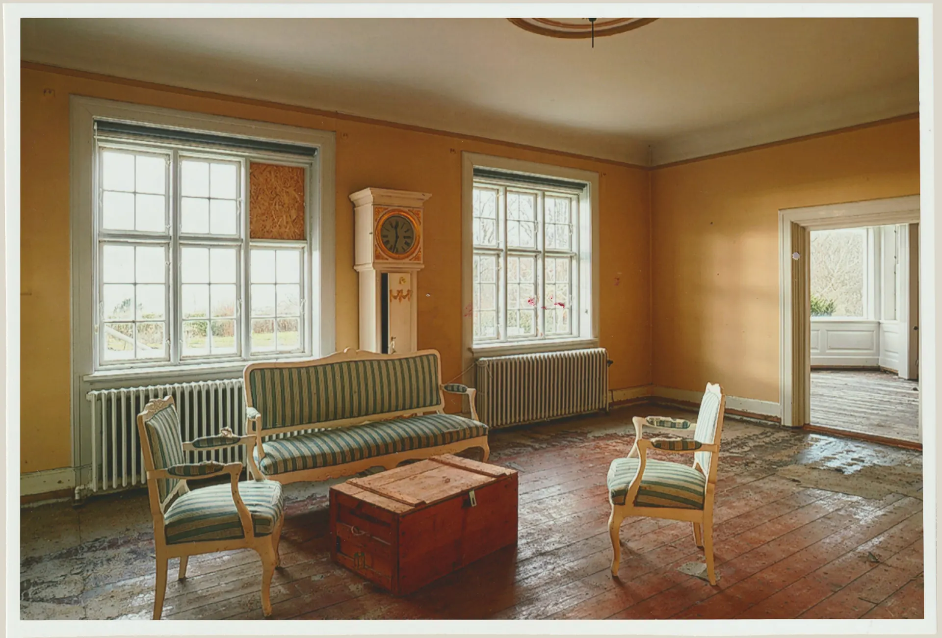A restored Villa Hesnæs sitting room with pale chairs and warm ochre walls.