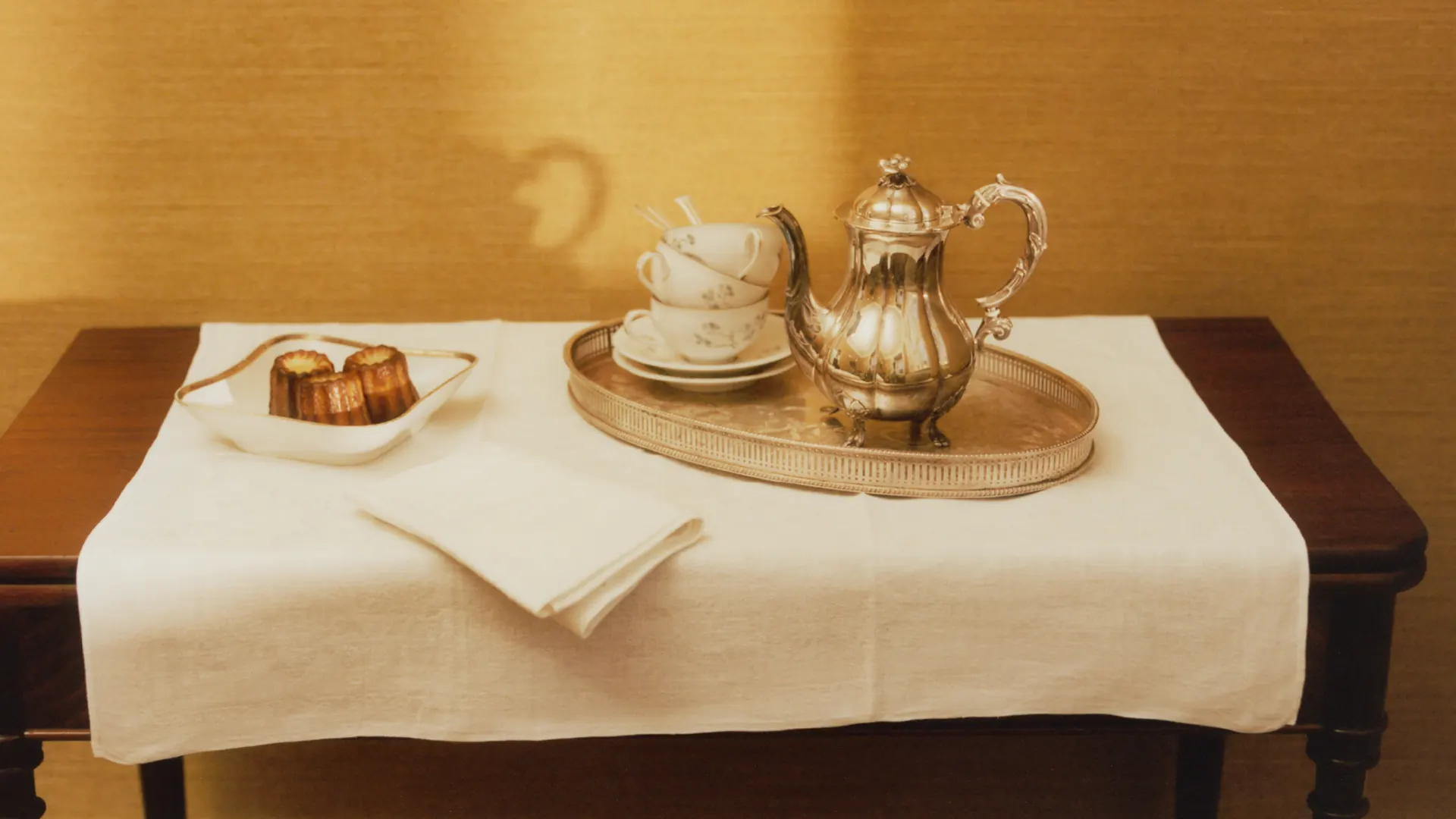 A silver coffee pot, cups, and canelés on a tray at Villa Hesnæs.